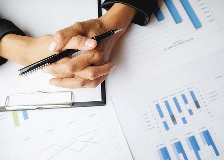 Hands pointing at charts and graphs on paper during a business meeting.