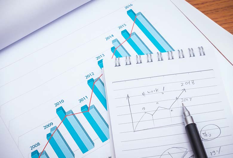 Close-up of financial charts and graphs with a pen on paper.