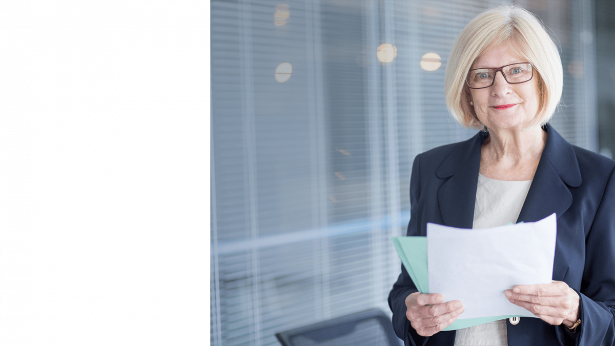 Professional woman in suit holding documents in modern office.