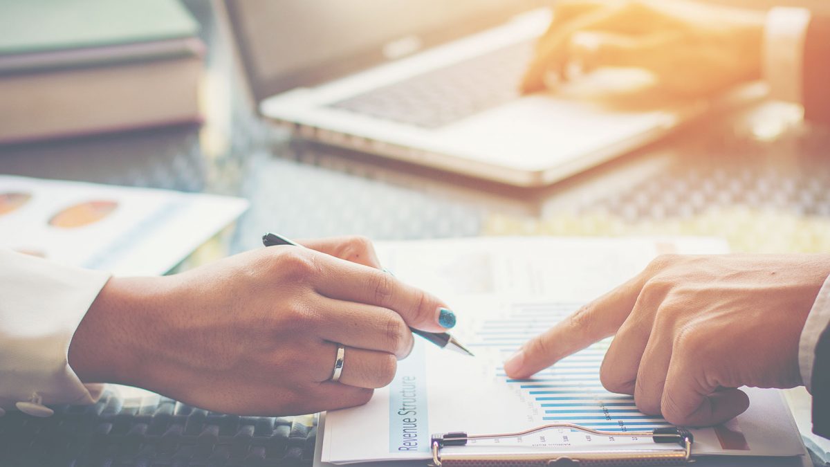 Two people reviewing a document with charts and graphs.