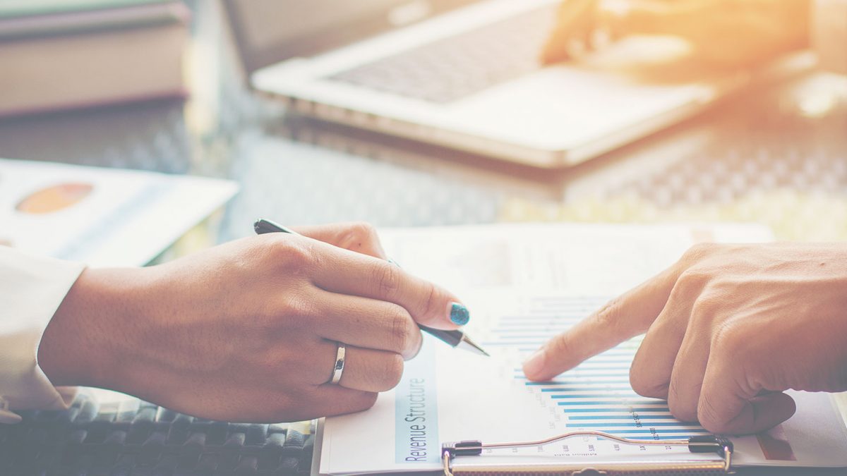Two people discussing financial documents with a pen and clipboard.